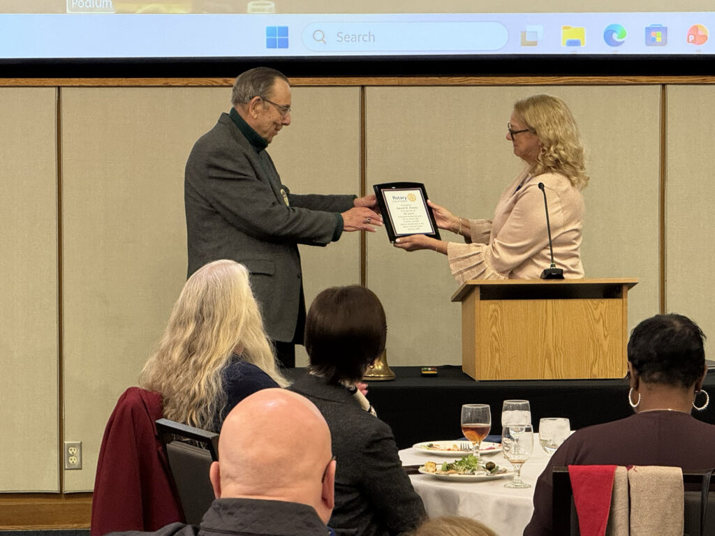 President Linda Osterfeld presents David H. Ponitz with a plaque recognizing 50 years of dedicated service to the Club and the community.