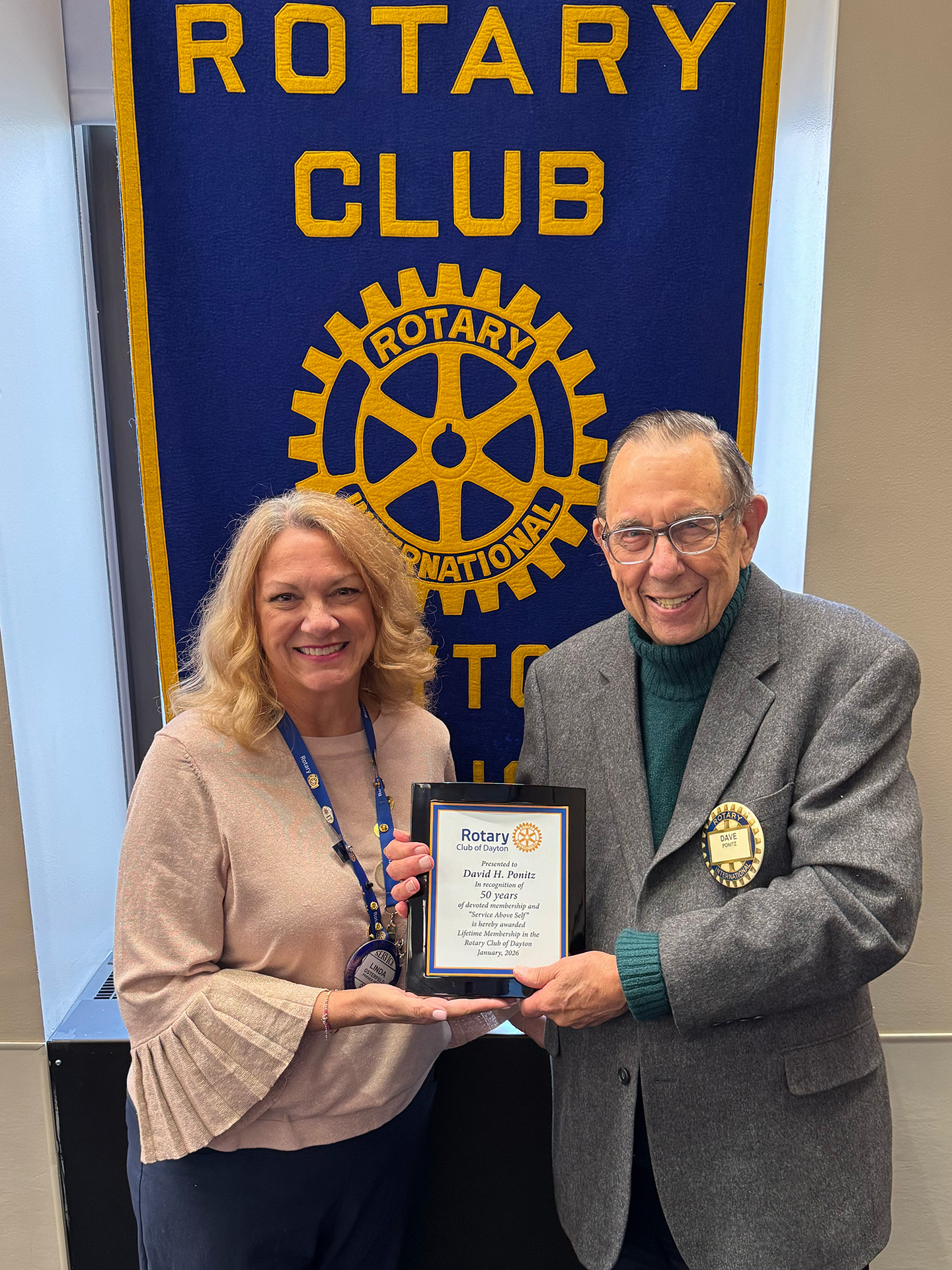 President Linda Osterfeld presents Dr. David H. Ponitz with a plaque recognizing 50 years of dedicated service to the Club and the community.