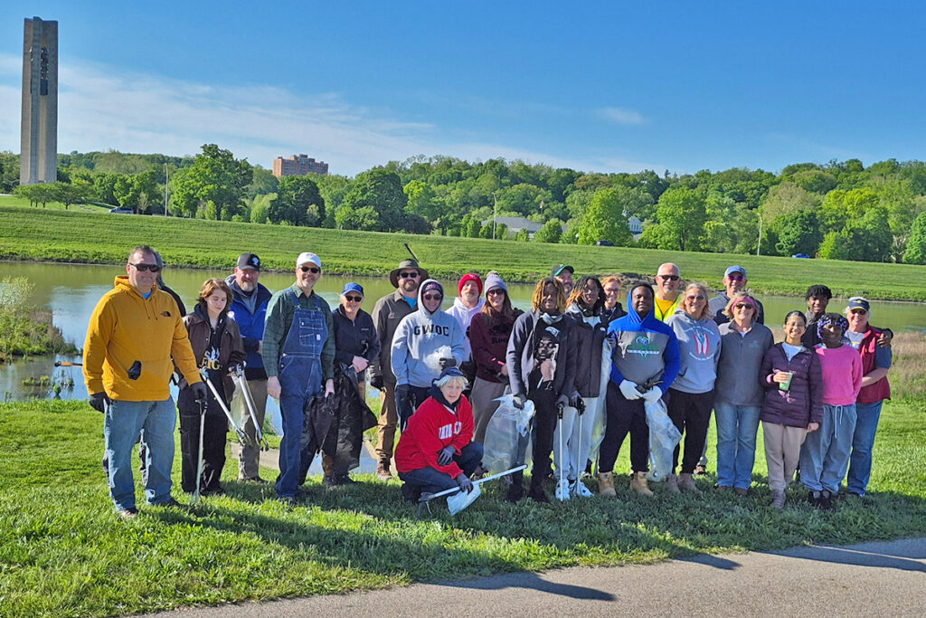 Rotary volunteers pose together in front of the Carillon Tower along the Great Miami River.